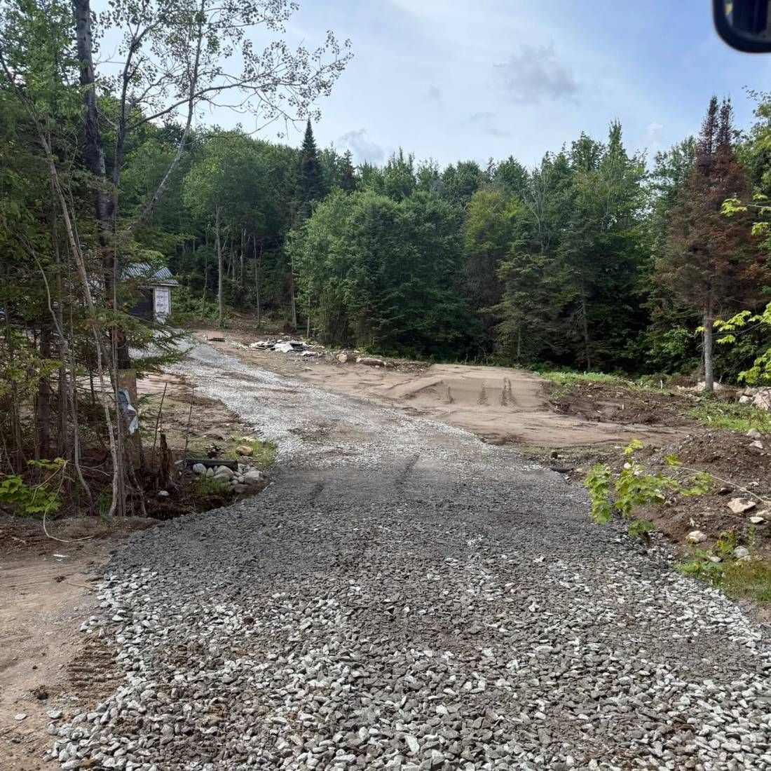 Chemin d'accès en gravier menant à un terrain boisé